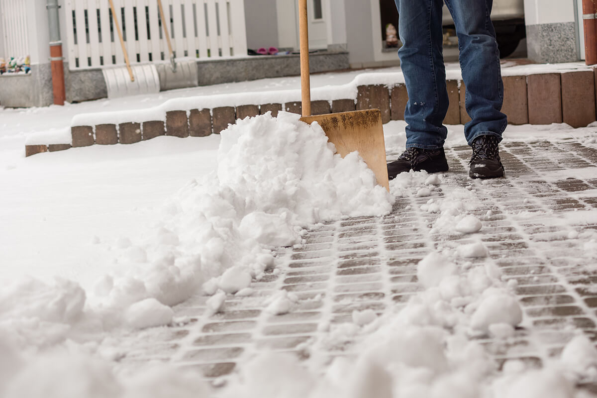 A person shoveling a brick driveway